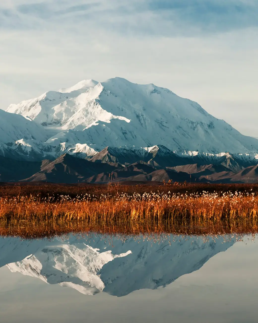 O Denali refletido num lago com a tundra dourada em primeiro plano