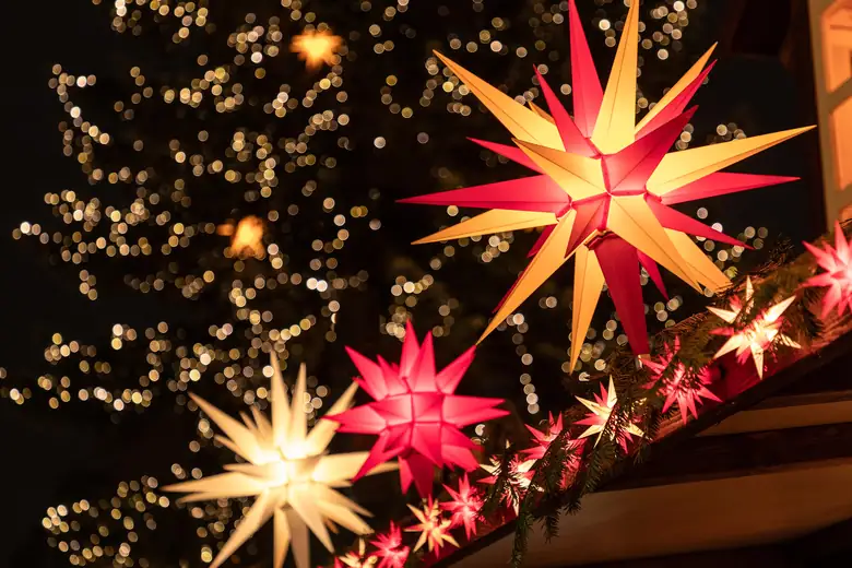 Estrelas da Morávia iluminadas decorando um mercado de Natal alemão à noite
