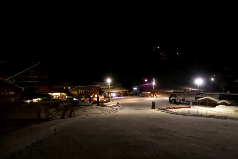 Vilarejo alpino iluminado à noite em meio à neve