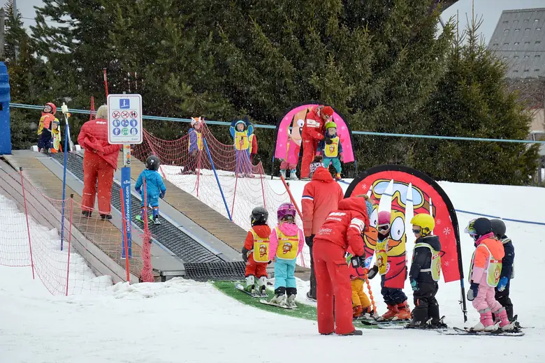 Crianças aprendendo a esquiar na neve com instrutor