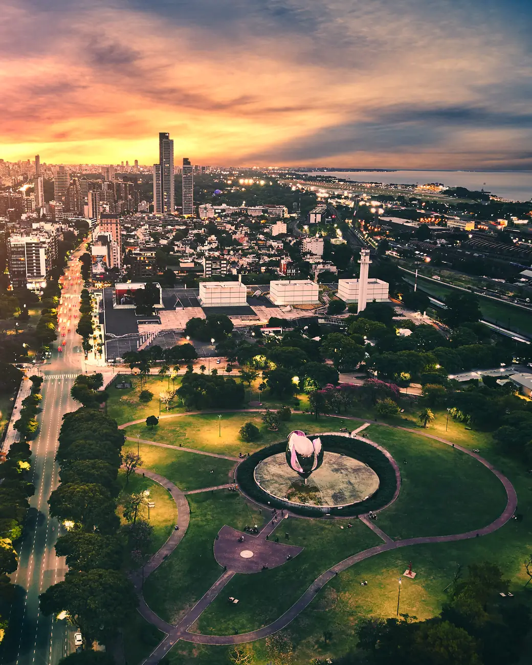 Vista aérea de Buenos Aires ao entardecer, com a Floralis Genérica entre parques e o Rio da Prata ao fundo