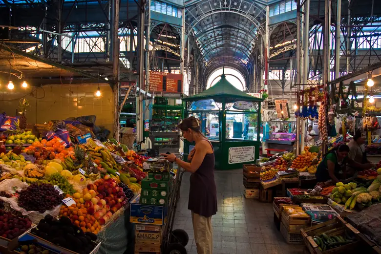 Interior do Mercado de San Telmo, com bancas de frutas sob a estrutura de ferro do século XIX