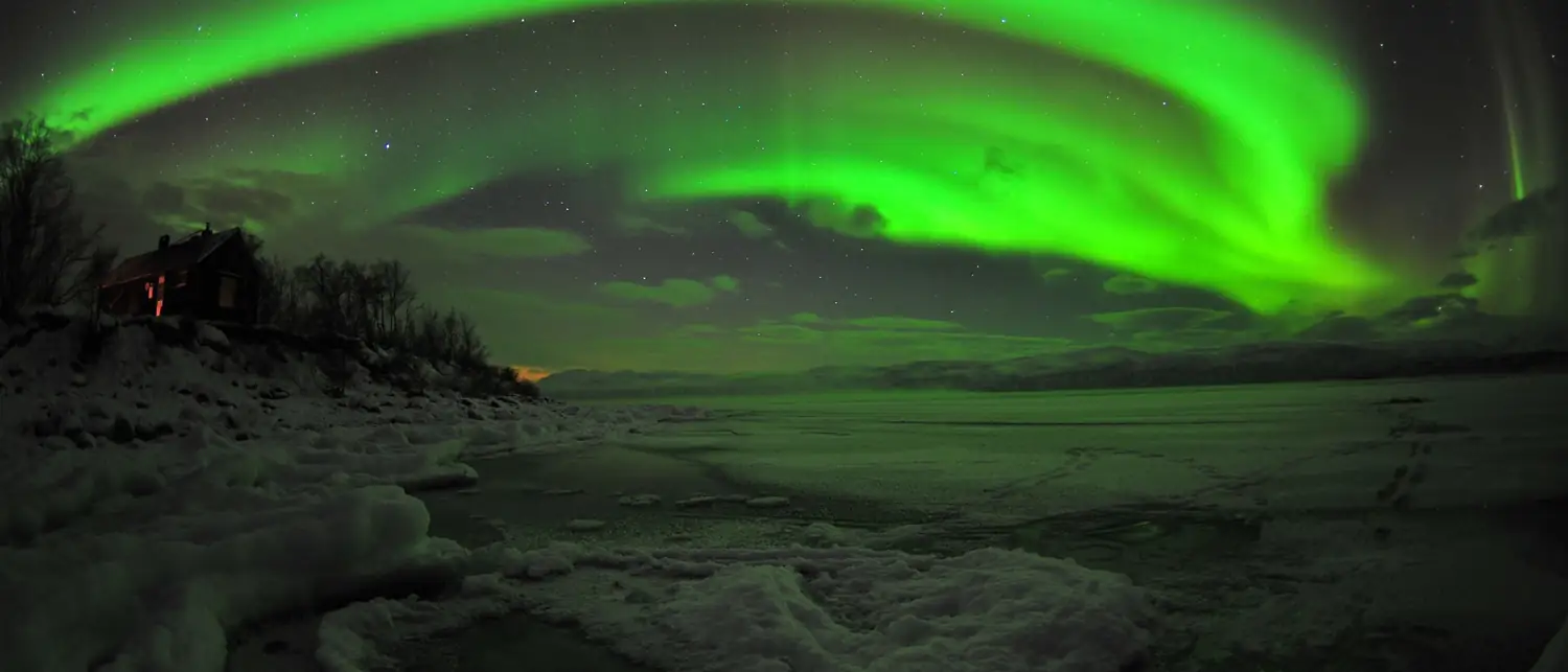 Aurora boreal em faixas verdes cobrindo o céu do Ártico