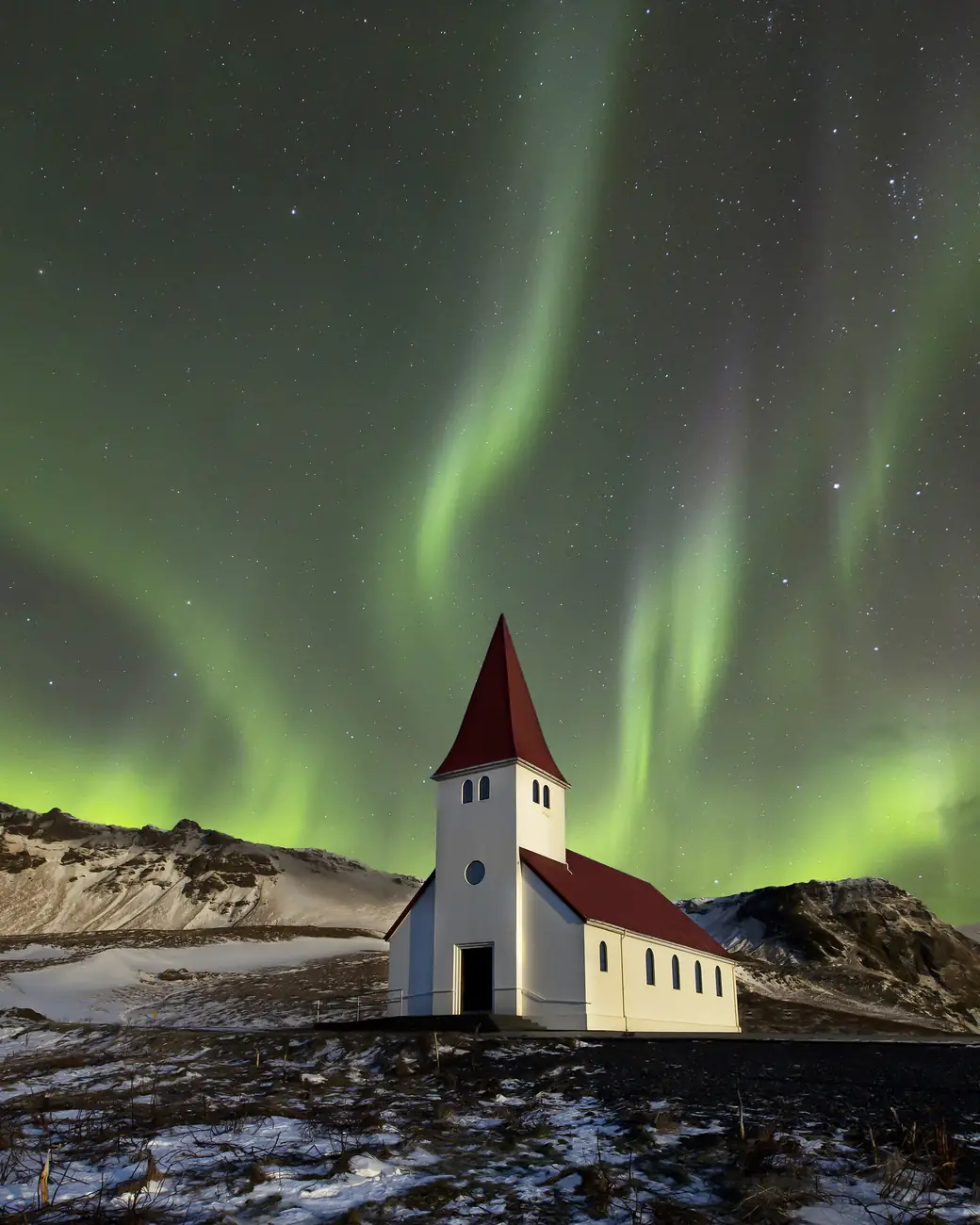 Aurora boreal sobre paisagem vulcânica e nevada da Islândia