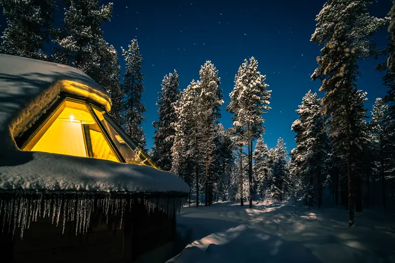 Interior de um iglu de vidro com vista para o céu estrelado da Lapônia