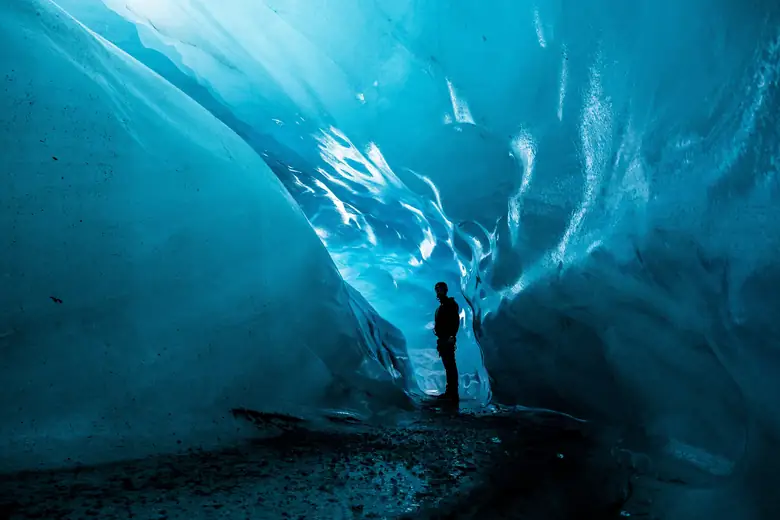 Interior azul translúcido de uma caverna de gelo em geleira islandesa