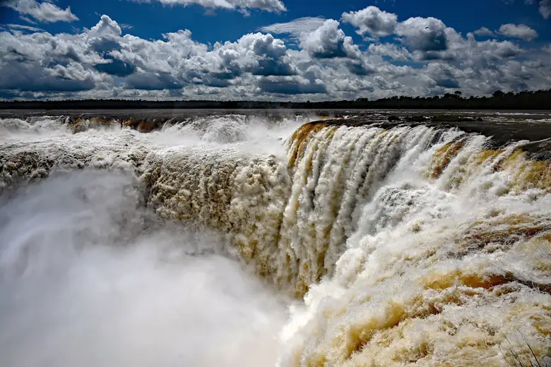 Borda das quedas do Iguaçu, com a névoa subindo sob céu de nuvens