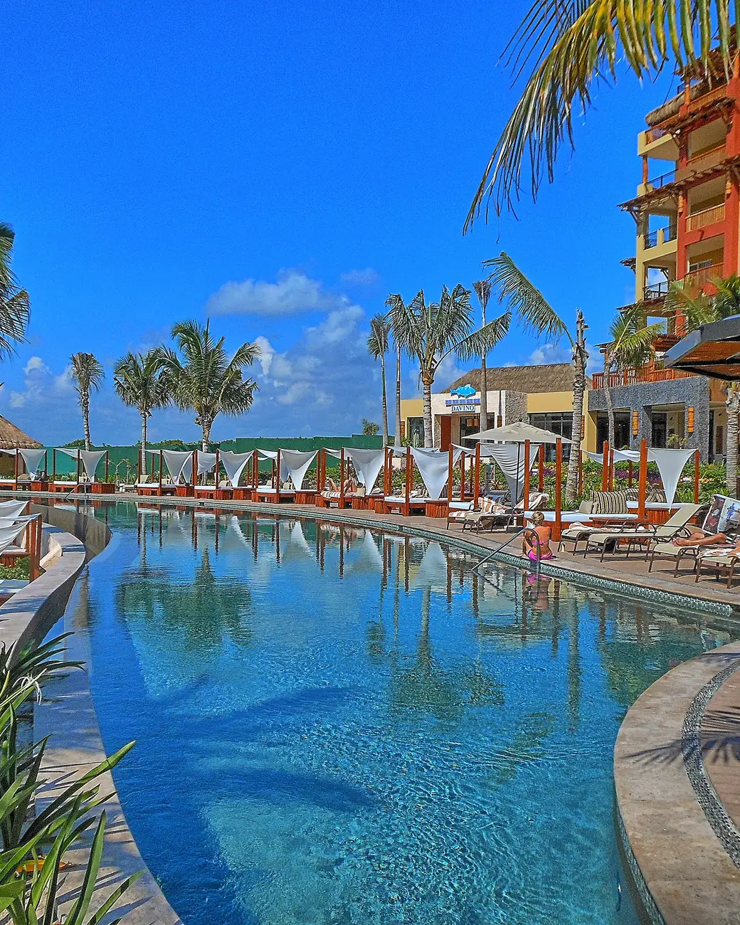Piscina de resort desenhada entre palmeiras de frente para o Caribe