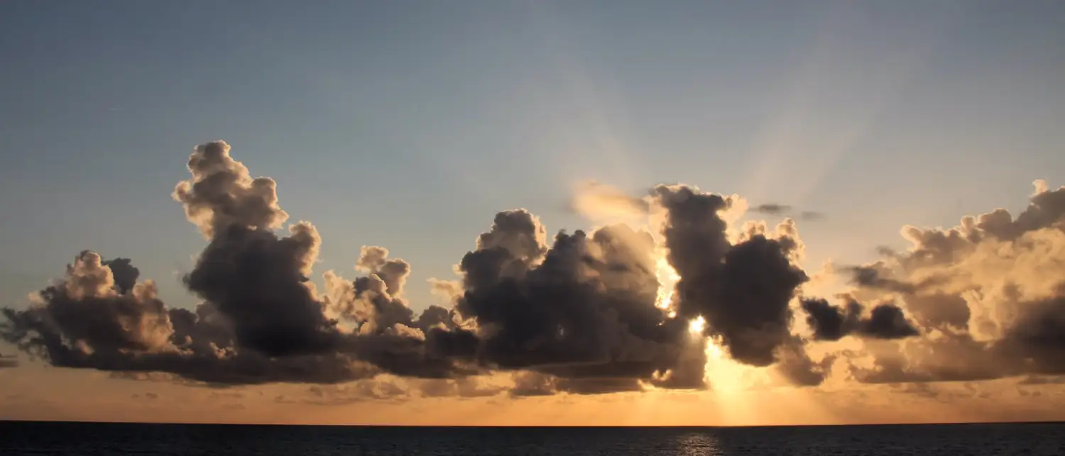 Pôr do sol dourado sobre o mar aberto, visto do deck de um navio