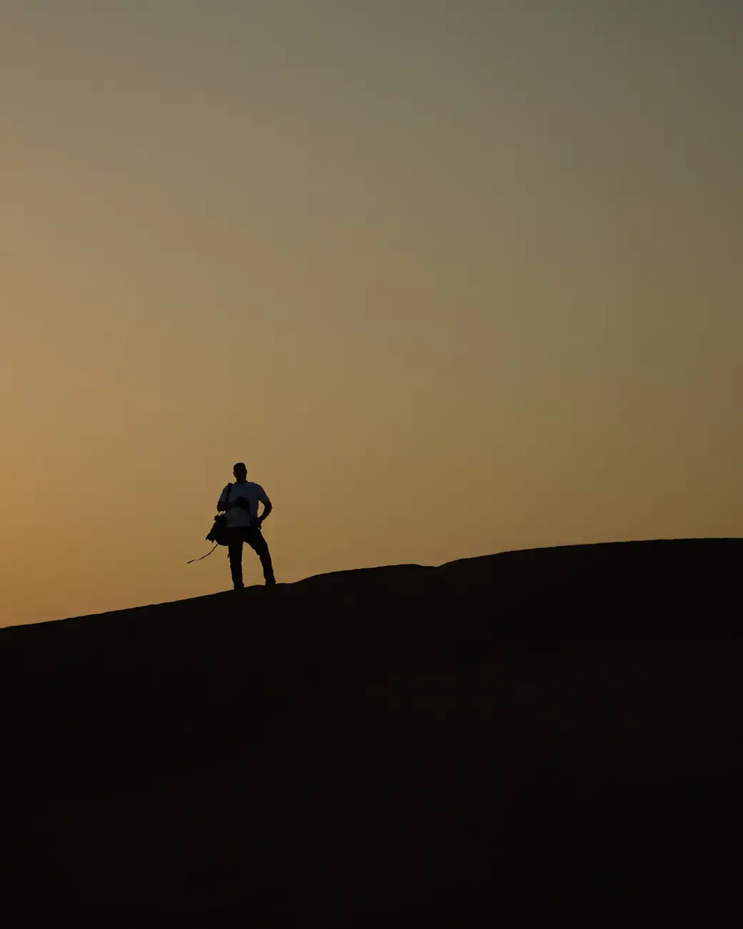 Silhueta no alto de uma duna ao pôr do sol no deserto de Dubai