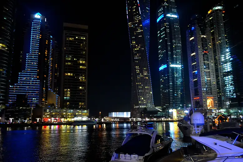 Iates na Marina de Dubai com arranha-céus iluminados ao fundo