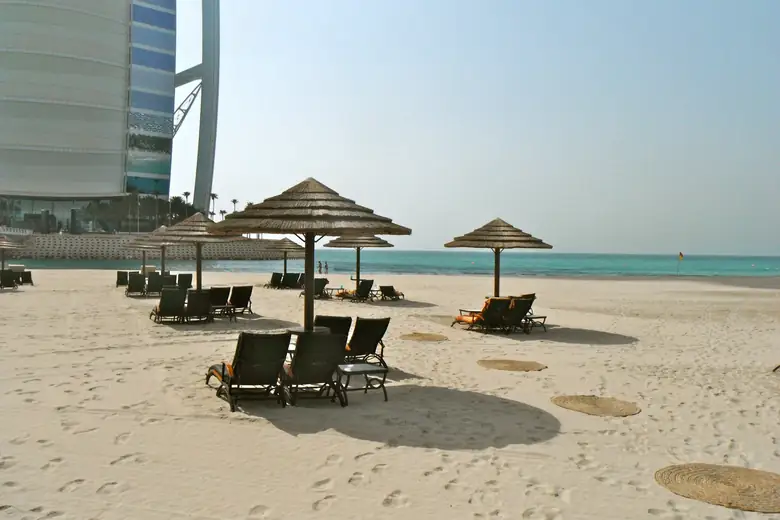 Espreguiçadeiras à beira do mar turquesa, aos pés do Burj Al Arab