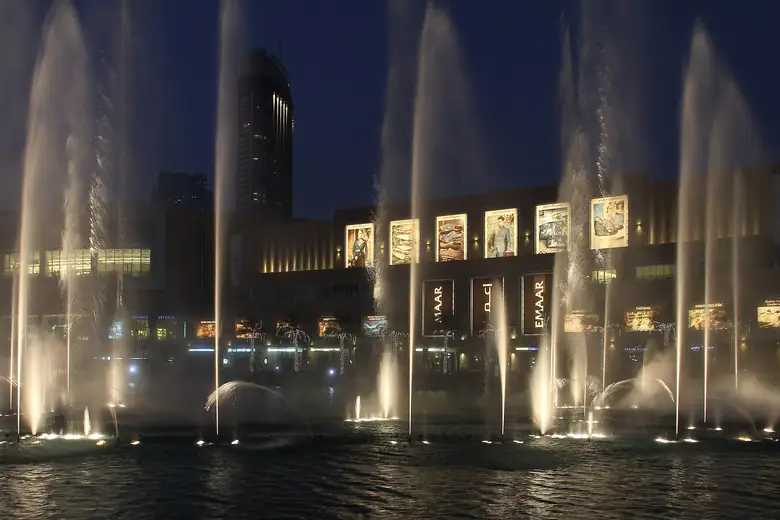 Show da fonte de Dubai iluminada ao anoitecer, com o Burj Khalifa ao fundo