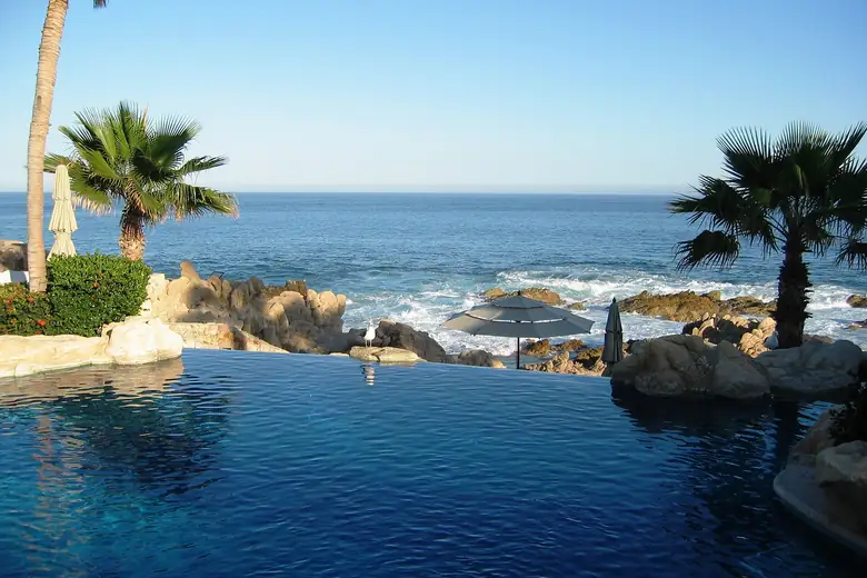 Piscina de borda infinita de resort sobre as rochas do mar em Los Cabos