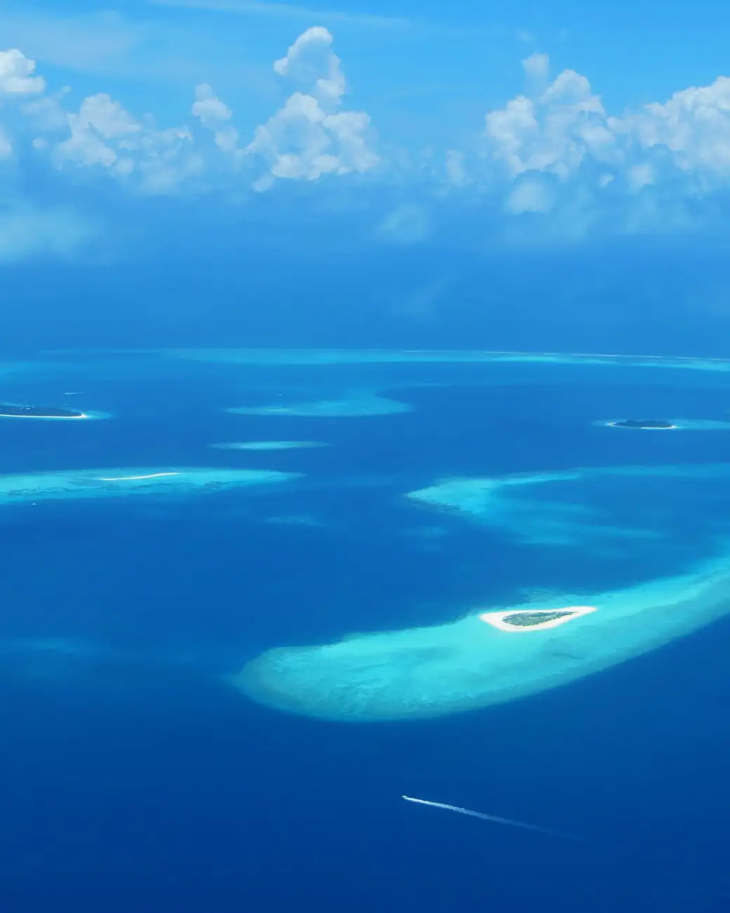 Atol das Maldivas visto do alto, com ilhas e recifes no azul