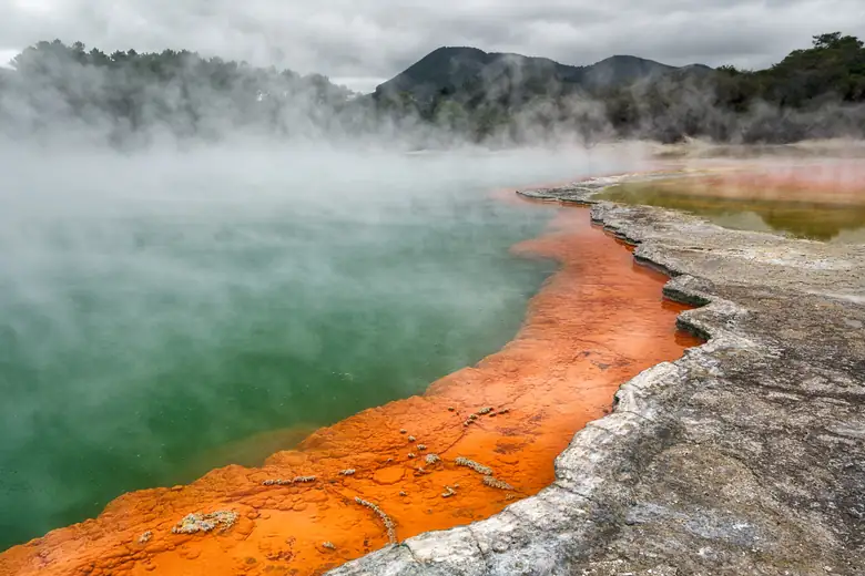 Champagne Pool fumegante com borda alaranjada em Wai-O-Tapu