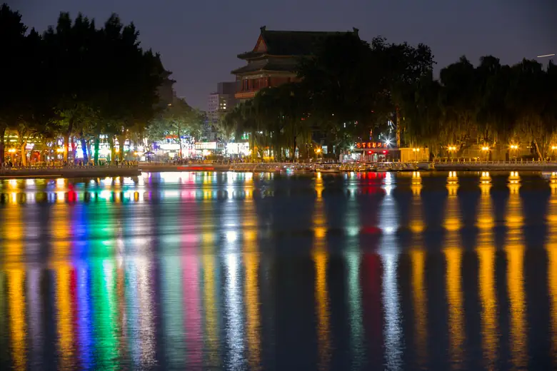 Luzes refletidas no lago Houhai ao anoitecer, com a Torre do Tambor ao fundo