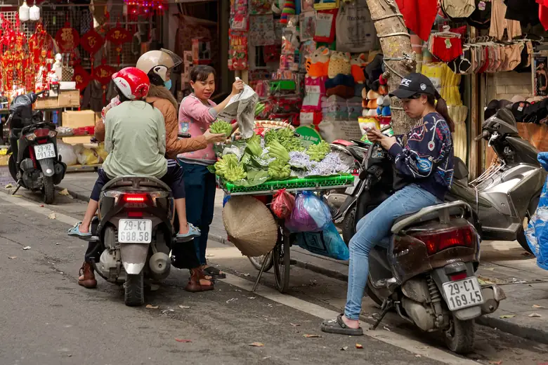 Cena de rua com vendedoras e motos no bairro antigo de Hanói
