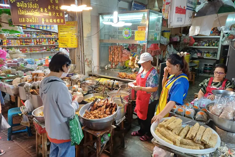 Barracas e panelas fumegando num mercado de comida de rua asiático