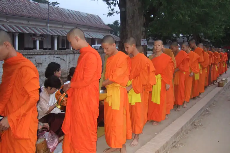 Monges budistas em fila na cerimônia de oferendas de Luang Prabang