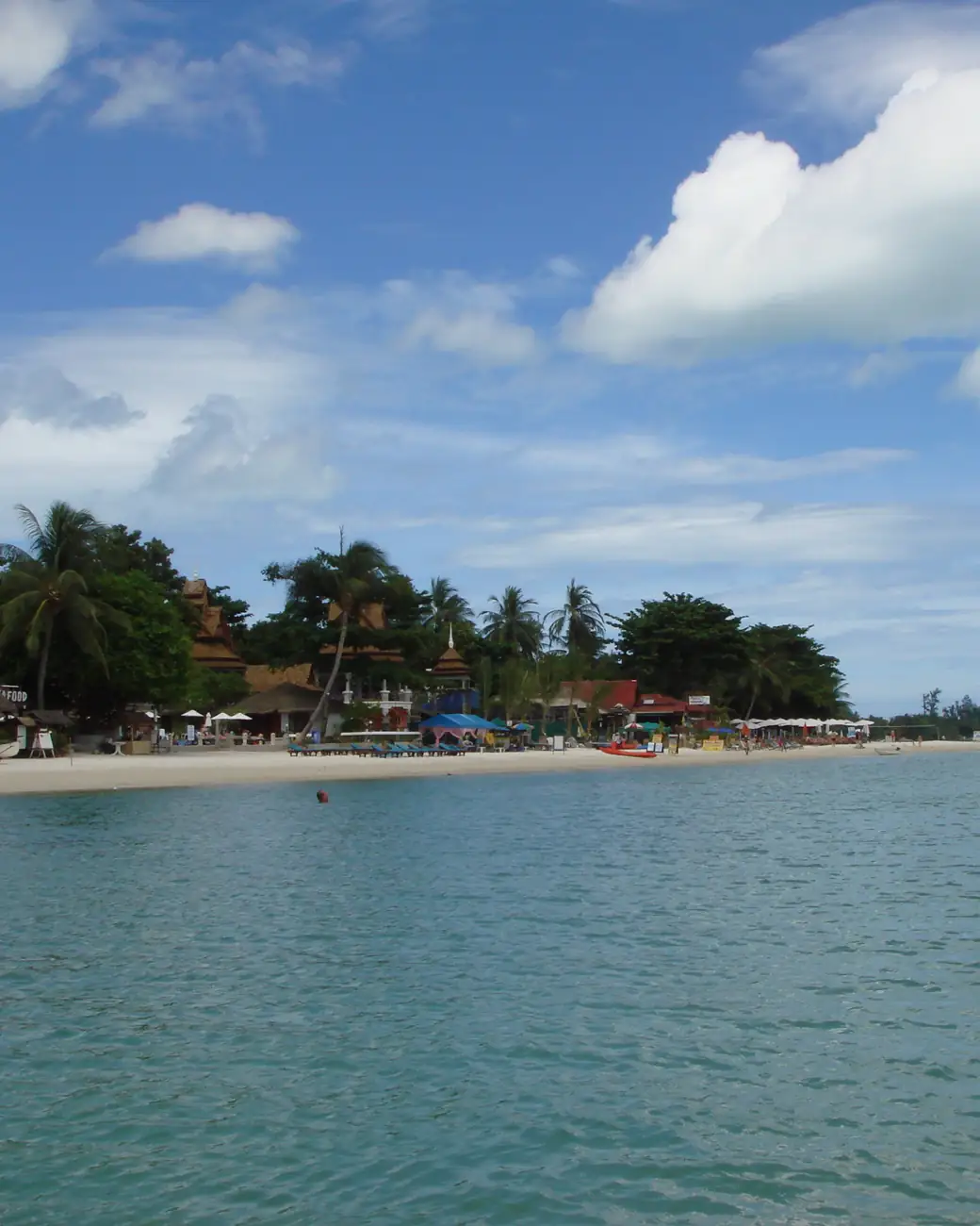 Coqueiros inclinados sobre praia de areia branca em Koh Samui, no Golfo da Tailândia