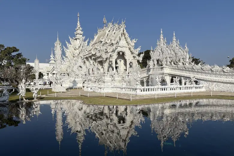 Templo Branco de Chiang Rai refletido, com sua ornamentação em gesso e espelhos