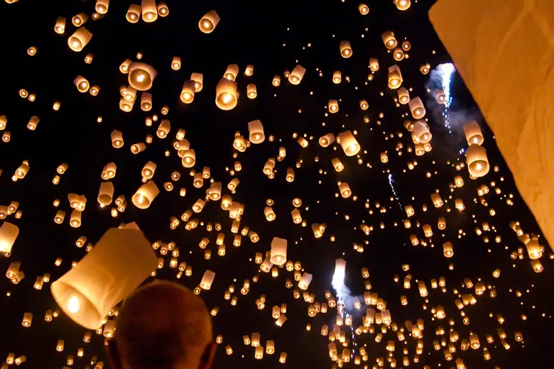 Milhares de lanternas subindo ao céu noturno no festival de Yi Peng