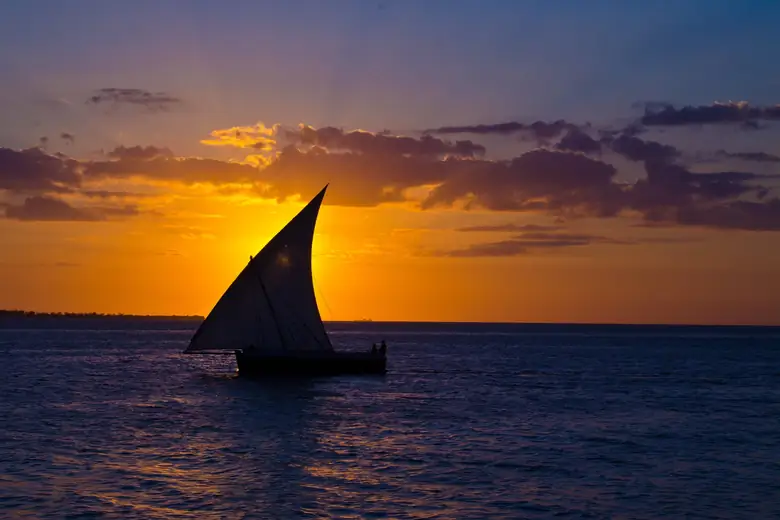 Dhow tradicional navegando ao pôr do sol em Zanzibar