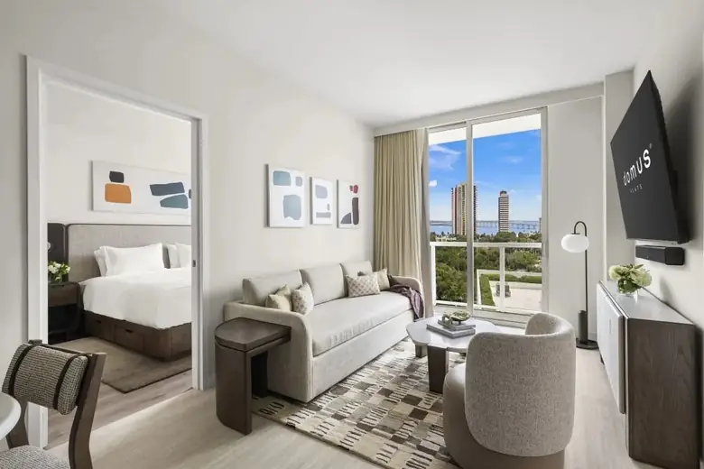 Sala de estar de um flat do Domus Brickell Park, com o quarto ao fundo