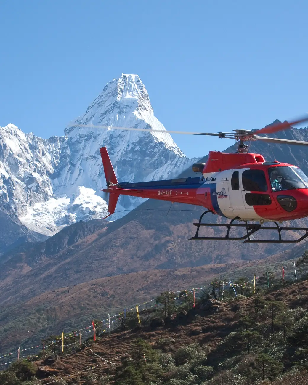 Helicóptero em voo diante de picos nevados